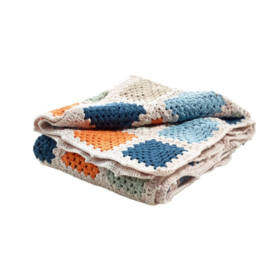 A neatly folded colorful hand-crocheted baby blanket displaying an array of blue, orange, and gray squares with a soft, textured surface visible.