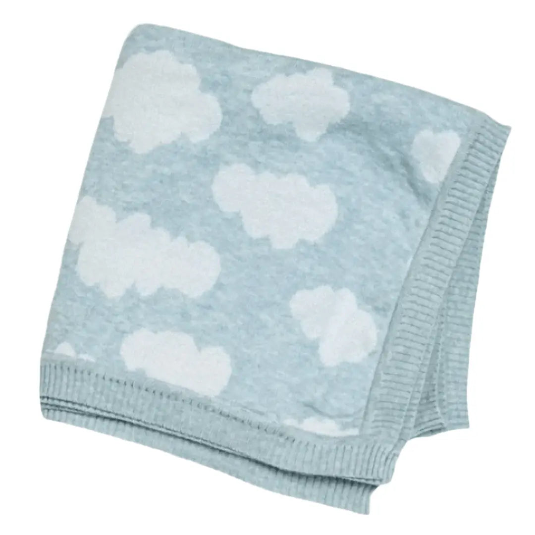 A folded baby blanket made from organic cotton. The blanket features a light blue background with a repeating pattern of white clouds, giving it a soft and dreamy appearance. The edges are neatly ribbed, adding a subtle, decorative detail to the cozy design. This cloud-themed blanket is perfect for creating a calming, nurturing environment for a baby.