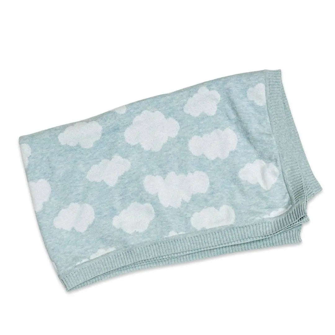 A folded baby blanket made from organic cotton. The blanket features a light blue background with a repeating pattern of white clouds, giving it a soft and dreamy appearance. The edges are neatly ribbed, adding a subtle, decorative detail to the cozy design. This cloud-themed blanket is perfect for creating a calming, nurturing environment for a baby.