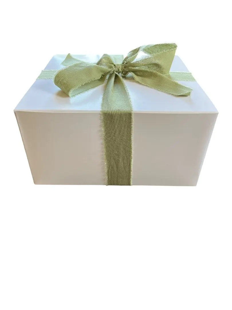 A white gift box, wrapped with a green thick ribbon.