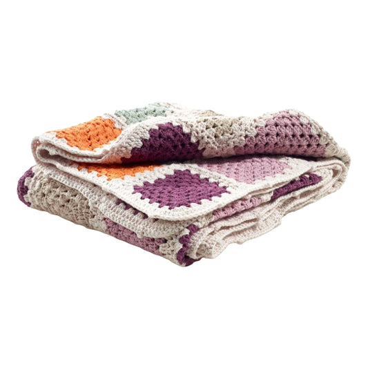 A neatly folded hand-crocheted baby blanket showcasing colorful squares in purple, orange, and white, emphasizing the blanket’s soft and textured fabric.