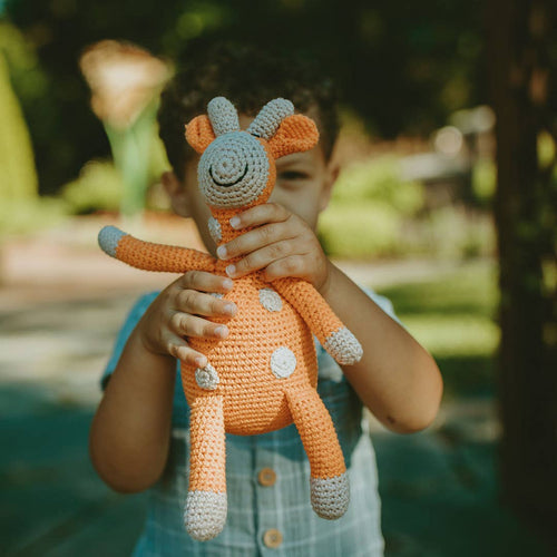 Child holding a crochet giraffe toy outdoors