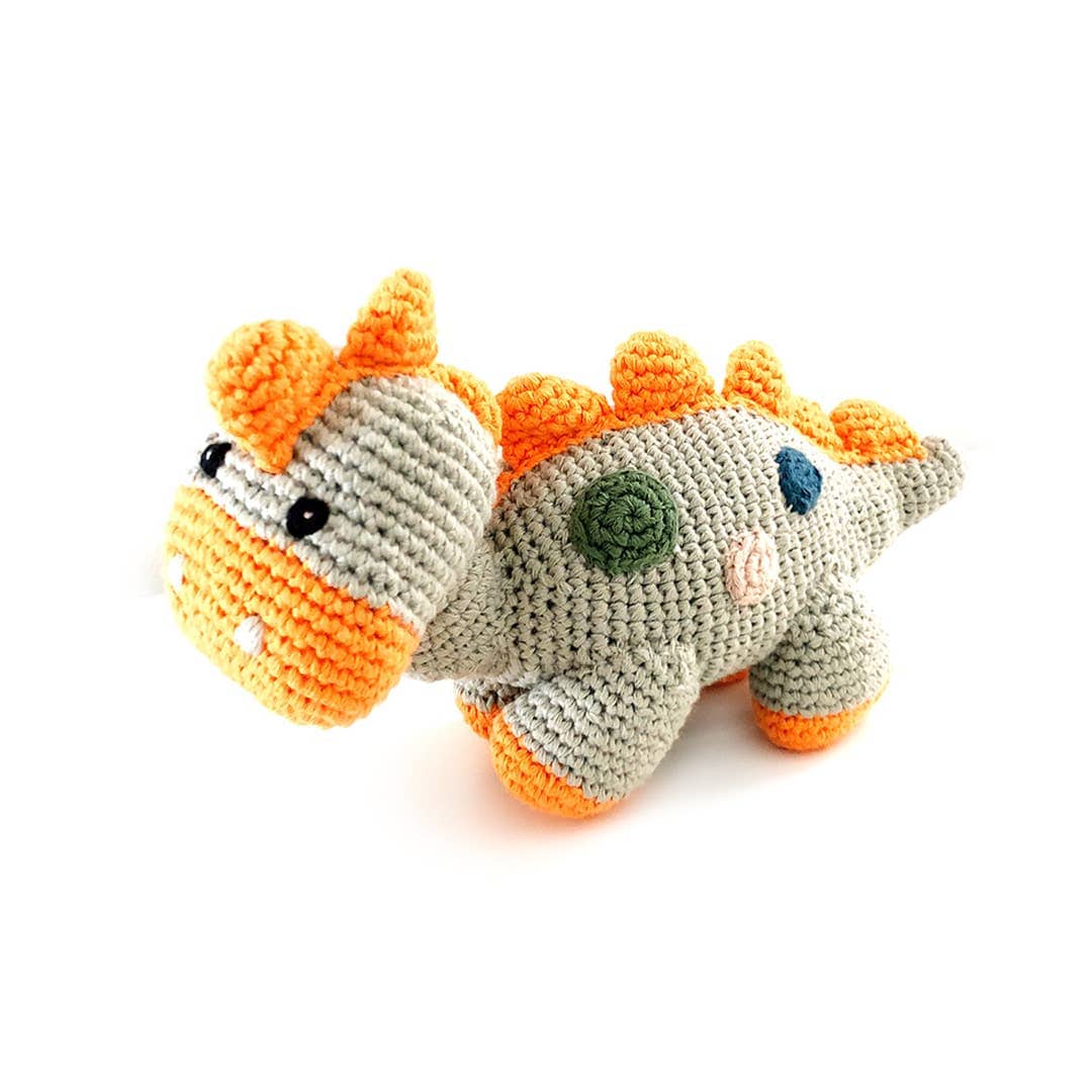 A crochet dinosaur toys with orange spikes on a white background