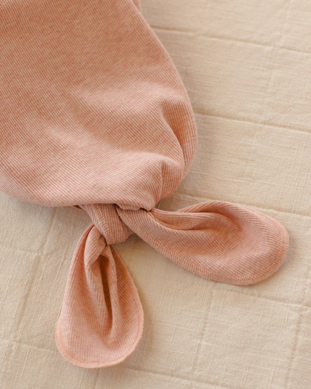 Pink knotted fabric on a beige textured background