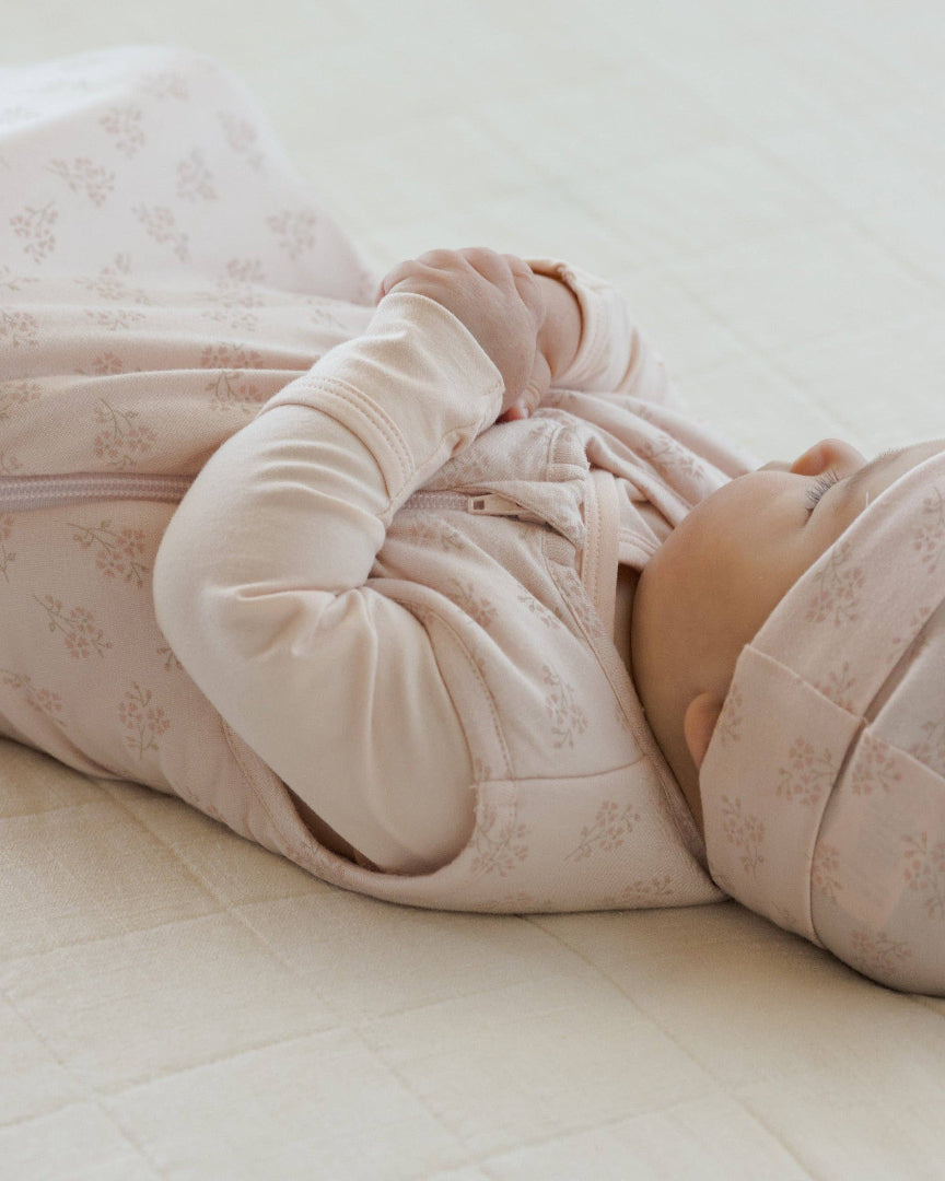Baby in pink floral outfit lying on a light surface