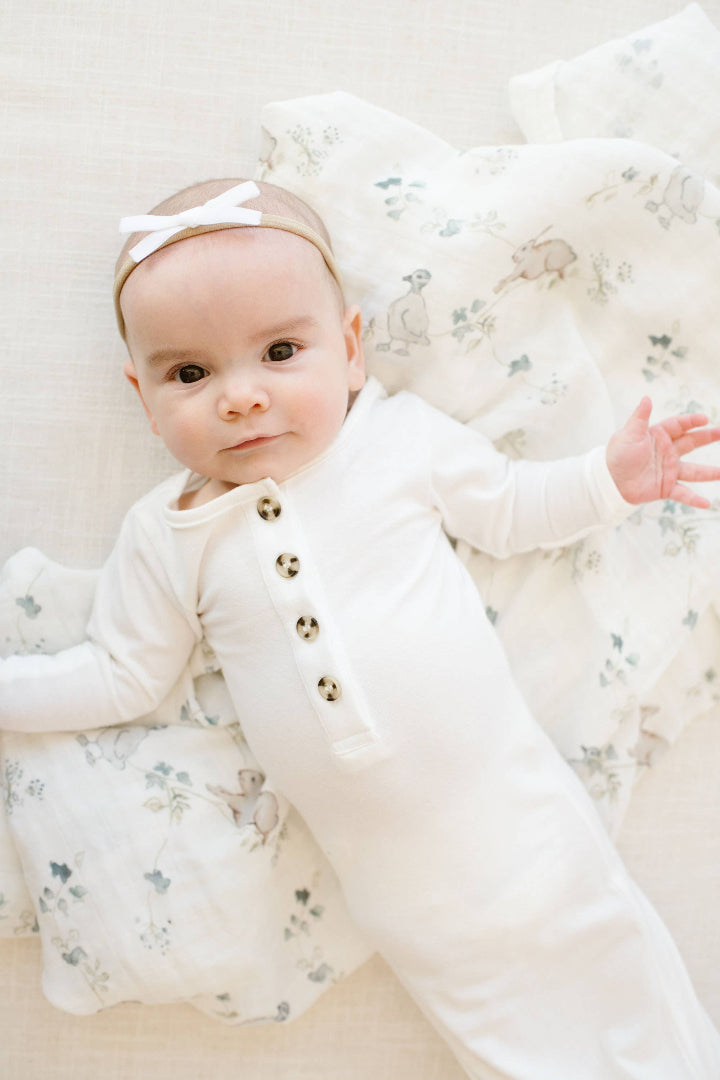 Baby in a white outfit with floral details on a soft white background