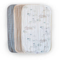 Three burp cloths, one with a plain design and the other with a pattern of bunnies and flowers, on a white background.