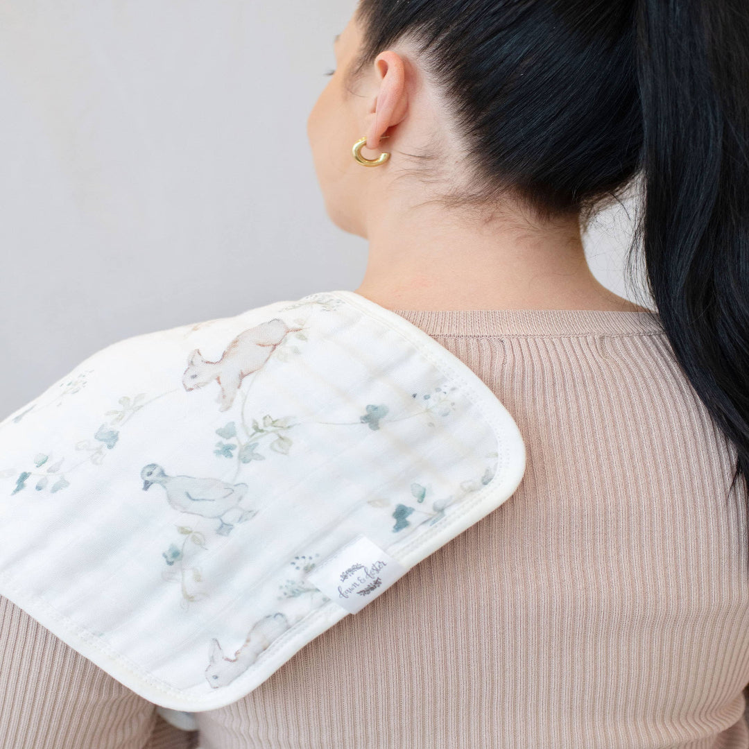 Person wearing a white bib with floral patterns on a plain background